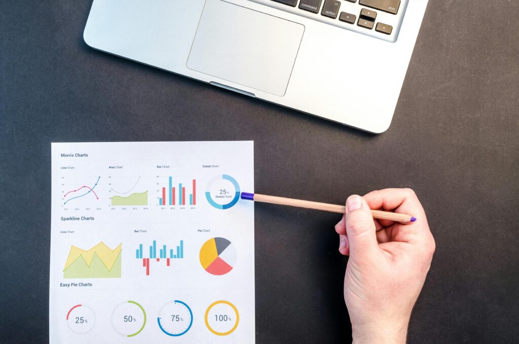 Google Analytics for SEO. Printed Google Analytics reports with charts, graphs, and traffic data on a desk, alongside a keyboard, pen, and smartphone.