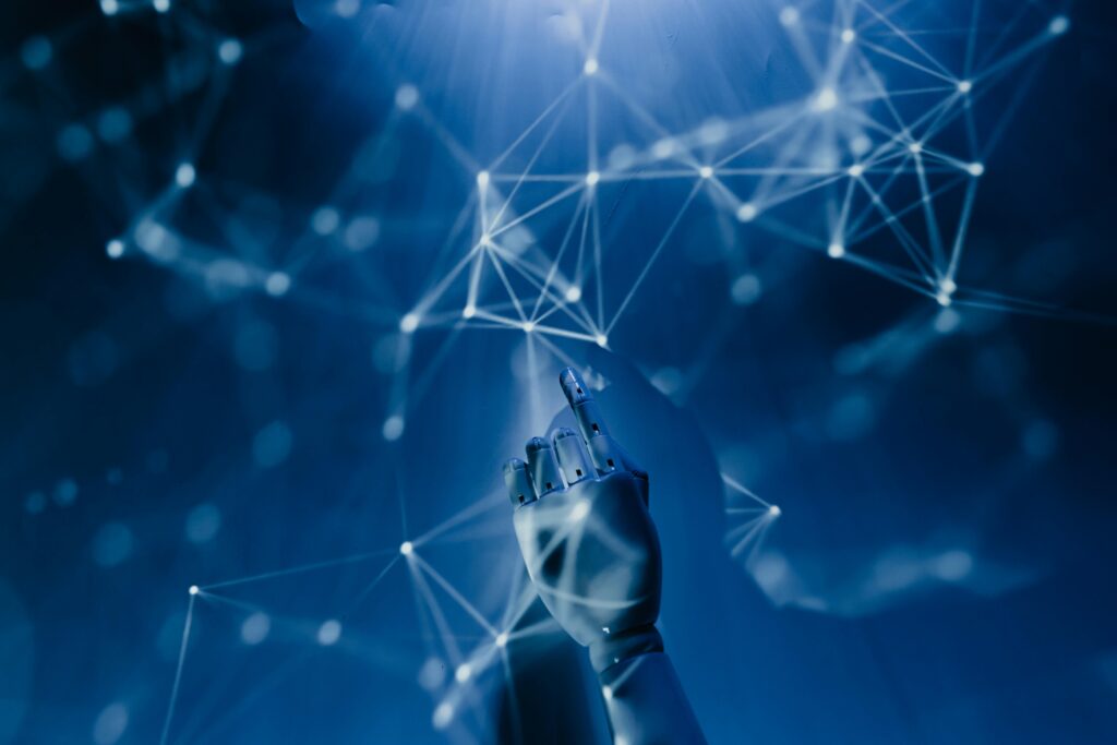 What Are the Best AI Tools for Digital Marketing . A robotic hand reaching towards a glowing network of interconnected nodes and lines, symbolizing artificial intelligence and digital connectivity, set against a futuristic blue background